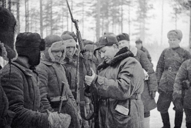 Бригадный комиссар Т. Штыков (на первом плане справа) рассматривает вооружение красноармейцев во время Советско-финской войны 1939-1940 годов. / Давид Трахтенберг / РИА Новости